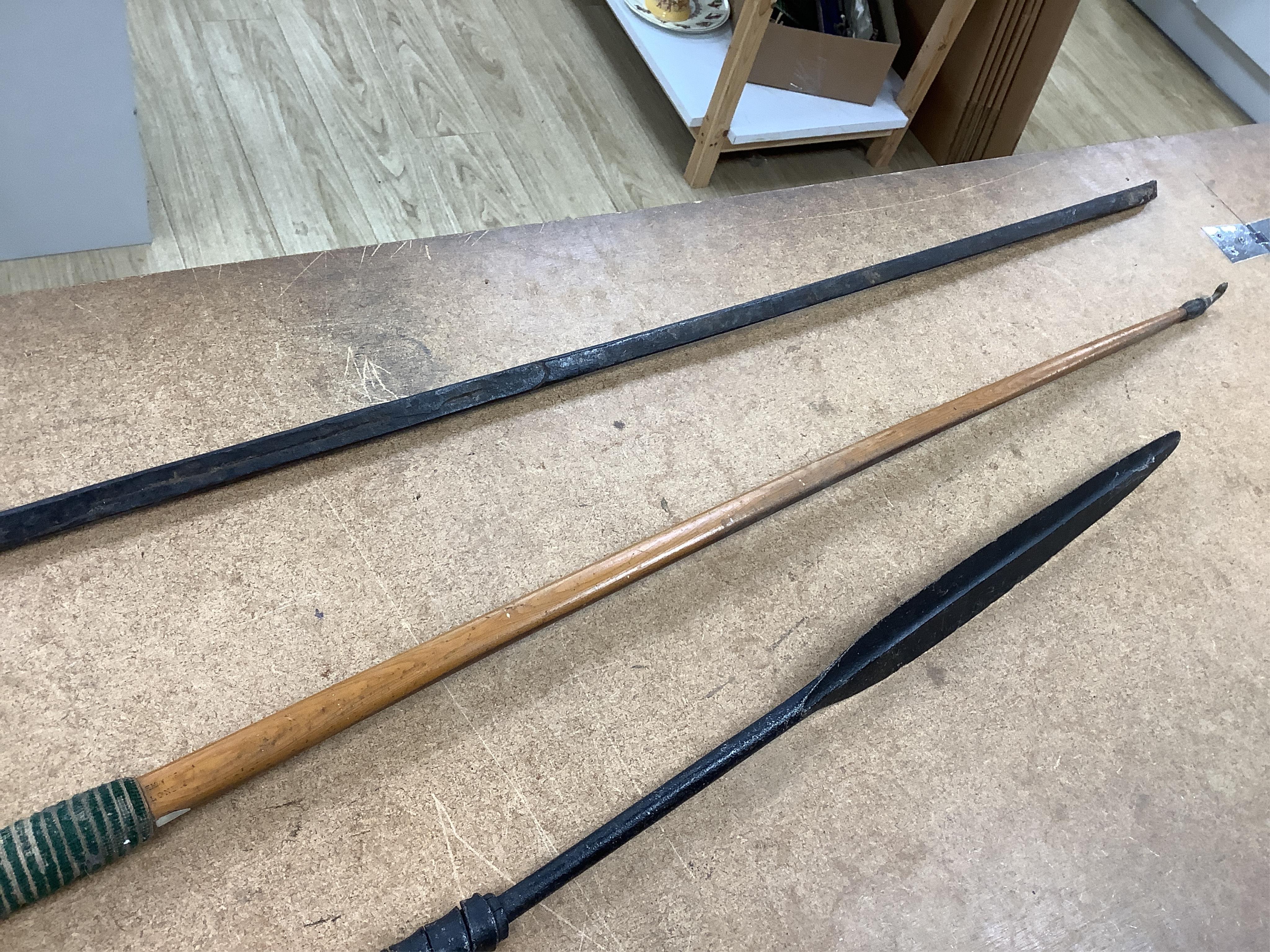 A collection of tribal spears, a fish hook, a cased snooker cue, etc.